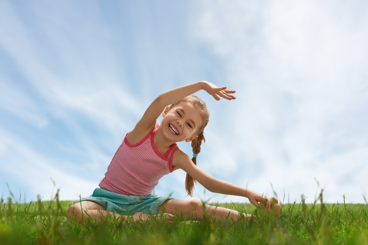 child practicing yoga on the grass outdoors
